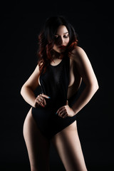 Fototapeta na wymiar Beautiful sexy woman in bodysuit posing on black background, low key studio shot