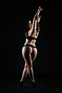 Beautiful sexy woman in lingerie posing on black studio background, low key studio shot