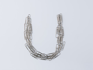 Letter U displayed with paperclips on white background