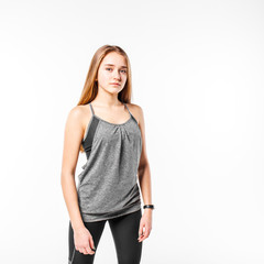 Young confident teenage fitness girl standing against white background