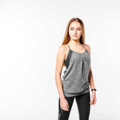 Fototapeta premium Young confident teenage fitness girl standing against white background