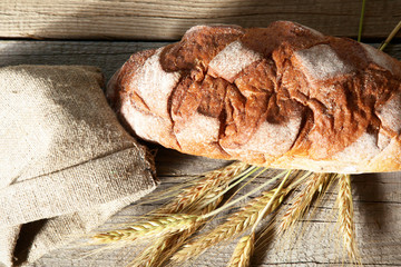 rustic crusty bread and wheat ears on a dark wooden table
