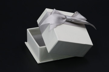Geöffnete weiße Geschenkbox mit Schleife isoliert auf schwarz
