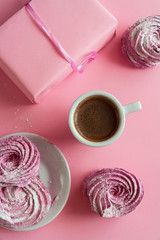 Gift in pink wrapping paper on a pink background. Pink marshmallows and an espresso cup. Wedding table. Holidays. Flat lay