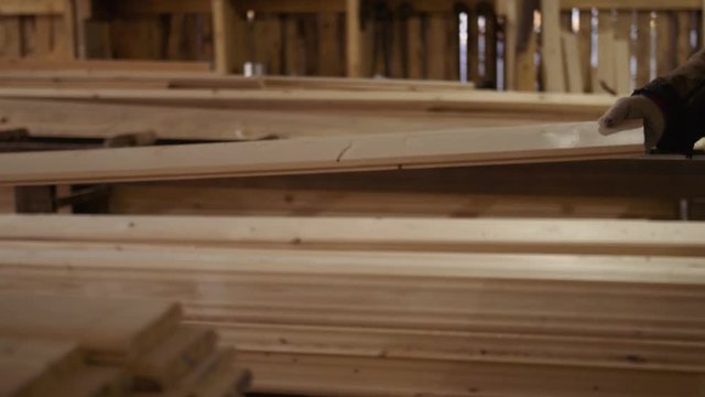 Wood board running out carpenter refiner workbench at sawmill facility, lots of sawdust