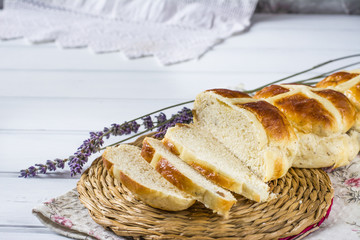 Easter hot cross buns with lavender flowers on napkin and wooden white and violet table. Easter baking.