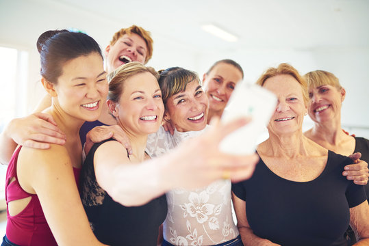 Laughing group of friends taking selfies in a dance class