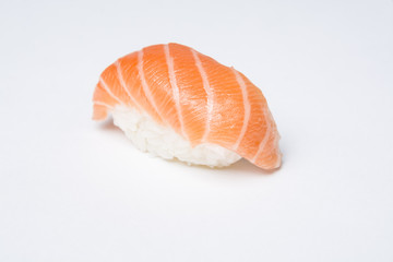 Close-up of traditional japanese sushi nigiri with a slice of raw salmon on white background.