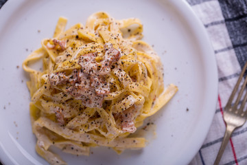 close up of pasta carbonara, on a white plate with background