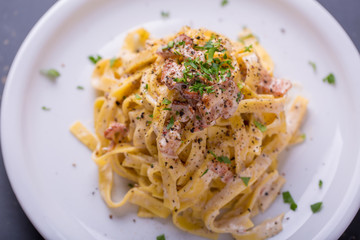 close up of pasta carbonara, on a white plate with background