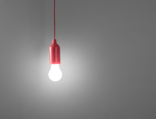Red lamp hanging on the cable in gray wall.