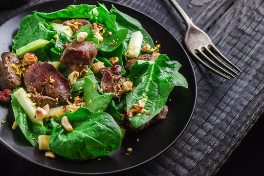 Green salad with liver and spinach on dark rustic background.