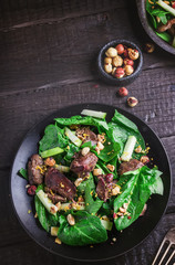 Green salad with liver and spinach on dark rustic background.