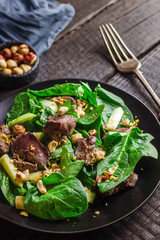 Green salad with liver and spinach on dark rustic background.