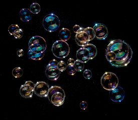 Rainbow soap bubbles on black background.