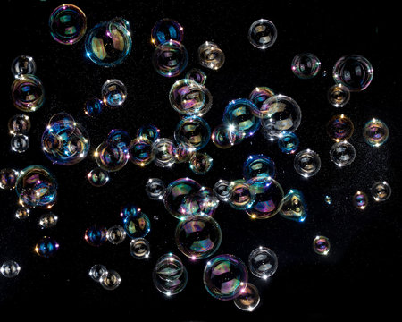 Rainbow soap bubbles on black background.