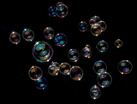 Rainbow soap bubbles on black background.