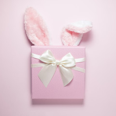 Bunny ears and present on plain pink background
