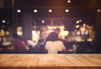Wood table top (Bar) with blur people siting night cafe,restaurant background .Lifestyle and celebration concepts
