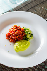 Tartare in hot sauce with avocado mousse top view vertical