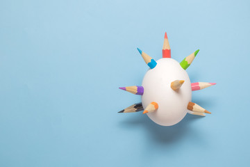 White easter egg with multicolored wooden crayons spears