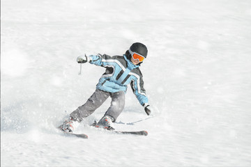 Fototapeta na wymiar The boy in a blue jacket on skis in mountains