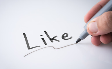 Hand holding black permanent marker and writing word ""on white background