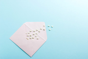 White envelope withhearts on blue paper or cardboard background.