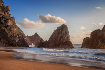 beautiful Atlantic ocean view horizon with sandy beach,  rocks and waves at sunset.  Sintra,  Portugal