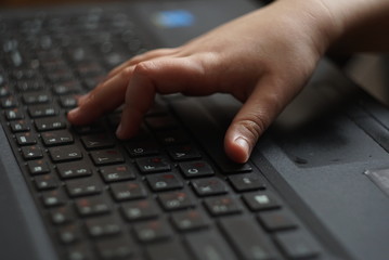 Closeup of a baby's hand on laptop keyboard 