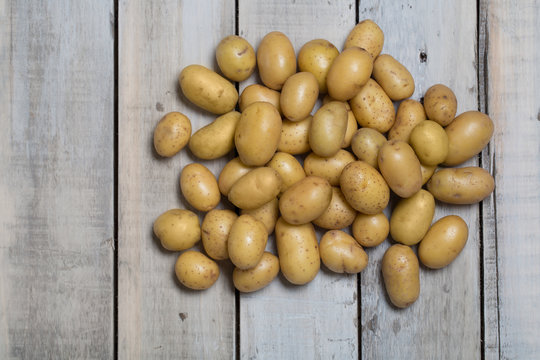 Raw baby potatoes on wooden background.