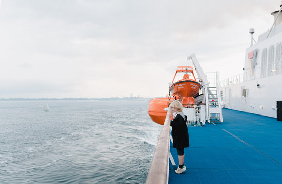 Side view of boy looking at view while standing near railing of ferry