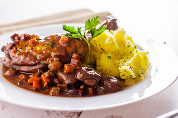 Rooster leg in wine with vegetable garnish side view horizontal