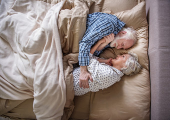 I love you. Top view of glad senior husband and wife sleeping in bedroom. They are hugging and...