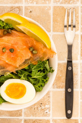 Bowl Of Smoked Salmon With Capers And Kale With A Boiled Egg And Lemon