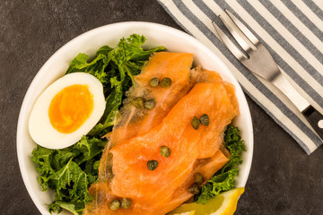 Bowl Of Smoked Salmon With Capers And Kale With A Boiled Egg And Lemon