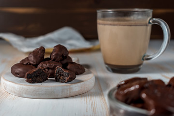 Prunes in chocolate on wooden background.