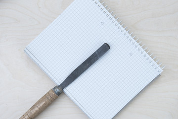 a professional chisel on a wooden background with a notebook