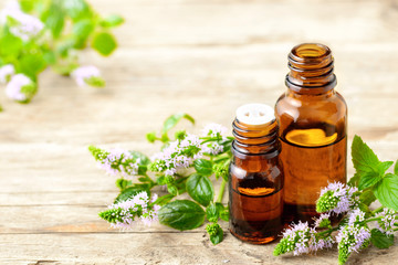 Peppermint essential oil and peppermint flowers on the wooden board