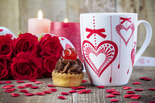Cupcake with cherry in front of bouquet of red roses
