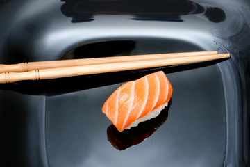 Sushi and chopsticks on black plate. Black wooden background. Close up