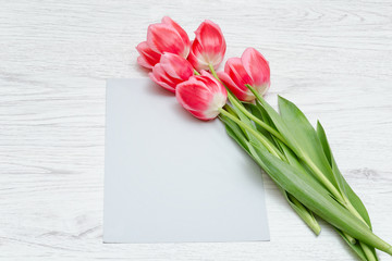 Clean card, pink tulips. Light wooden background. Top view. Space for text