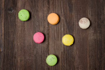 Fototapeta na wymiar Six multicolored macarons on a brown wooden table. Top view