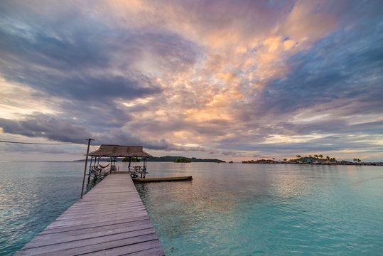 Tropical beach, caribbean sea, transparent turquoise water, remote Togean Islands (Togian Islands), Sulawesi, Indonesia. Dramatic sky at sunset.