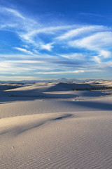 White sand dunes under wispy clouds in the evening