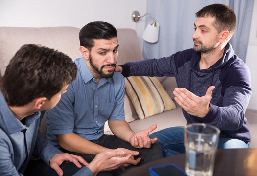 Three anxious men discussing on sofa