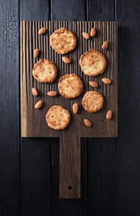 Flatlay of homemade almond cookies and raw almonds on oak board copy space