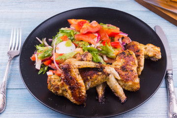 Fried chicken wings on rustic with salad close-up, top view