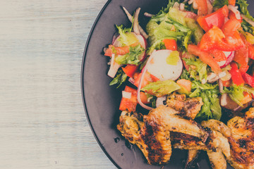 Fried chicken wings on a plate with vegetable salad close-up, copy space