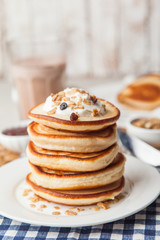 Pancakes stack on a white plate with cream and granola. Maslenitsa. Traditional Russian holiday.Shrove Tuesday, pancake day,